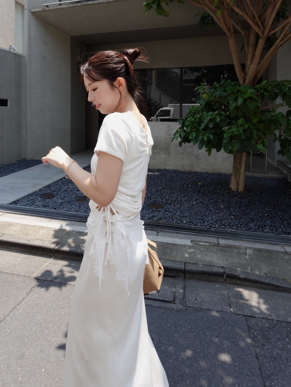 ホワイト系のTシャツ/カットソー、ホワイト系のスカート、ベージュ系のトートバッグを着用したレディースの夏コーディネートの2枚目の写真