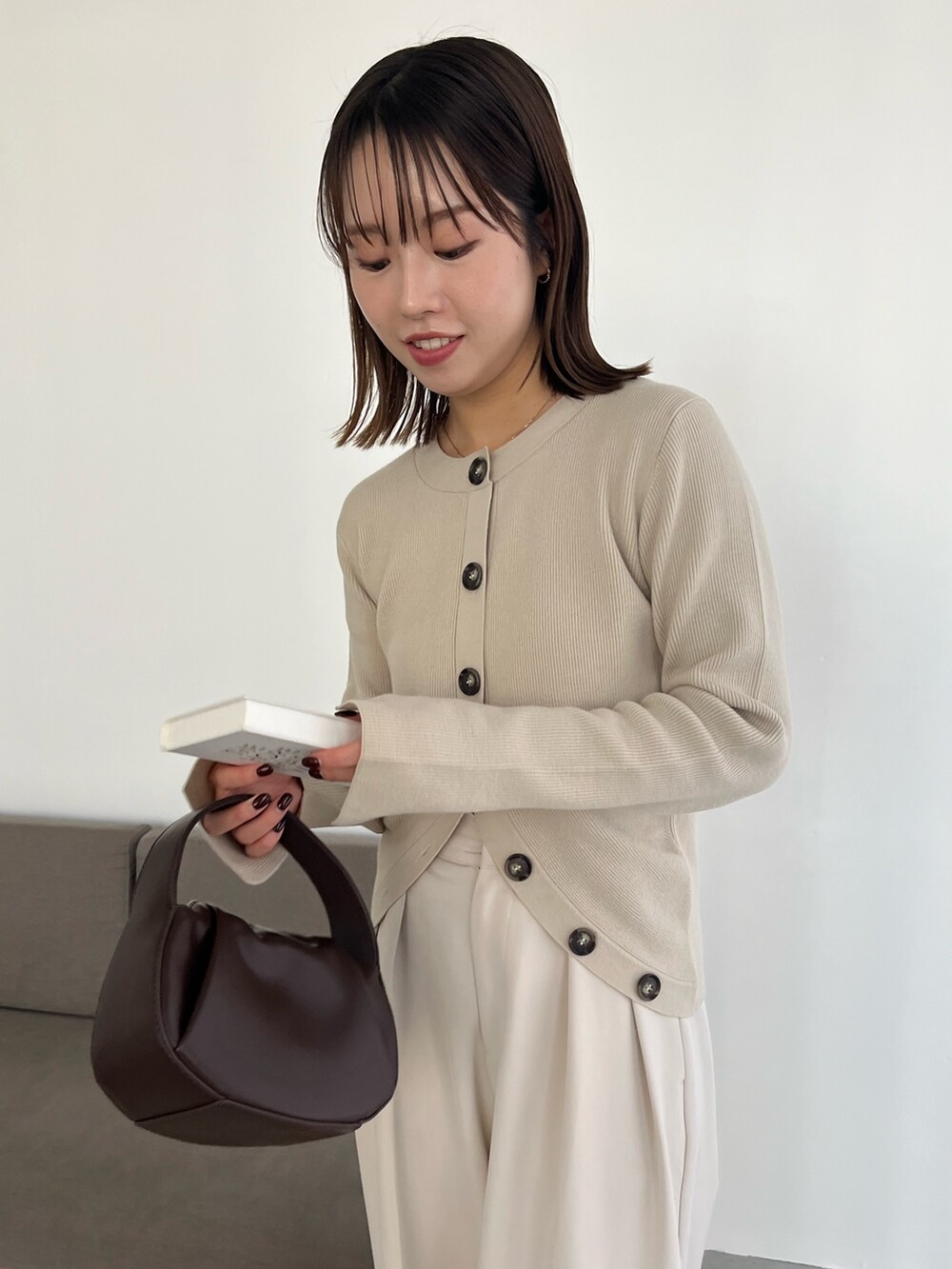 ブラック系のショルダーバッグ、ホワイト系のその他パンツ、ベージュ系のカーディガン/ボレロを着用したレディースの冬コーディネートの4枚目の写真