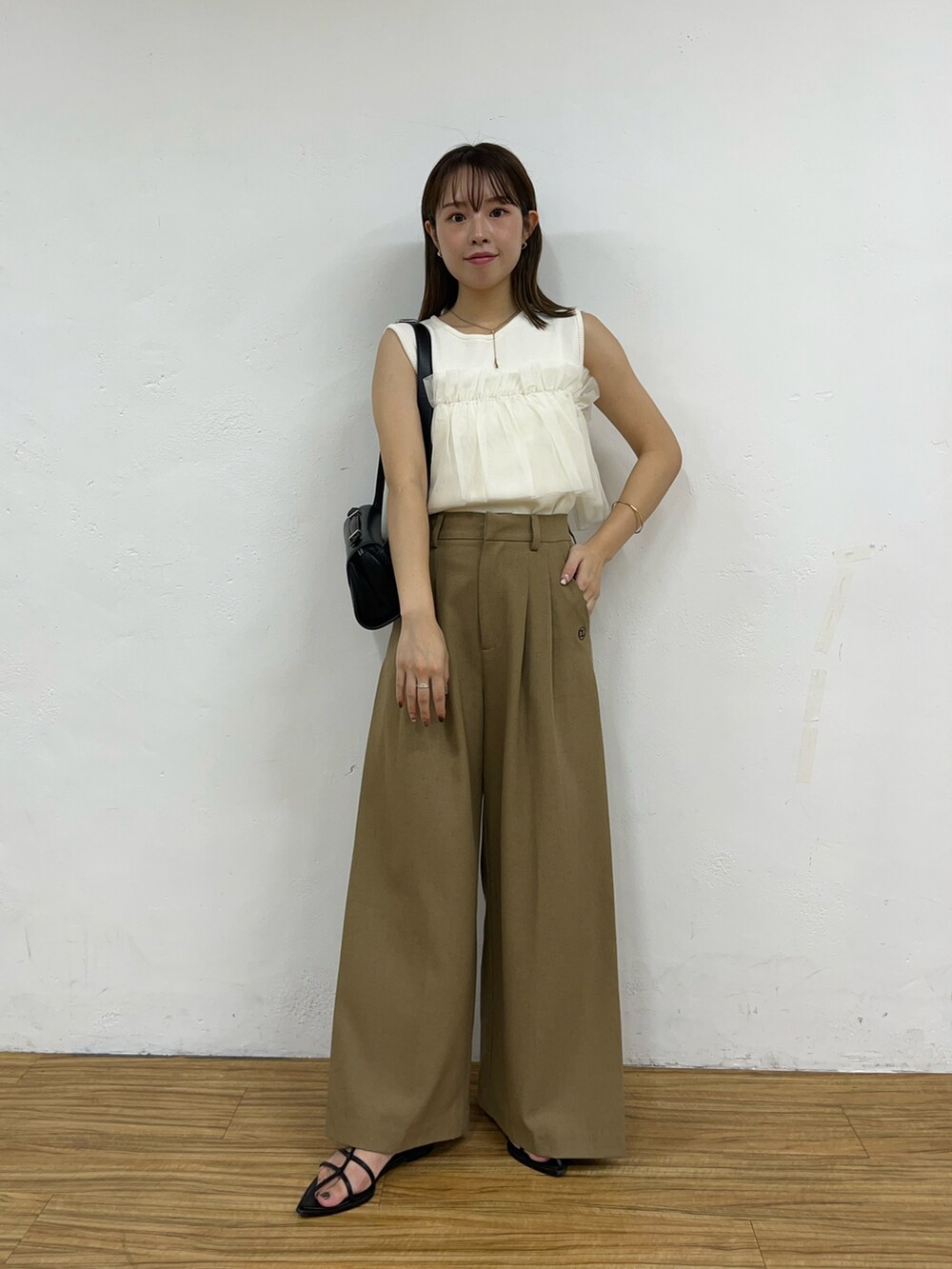 ホワイト系のニット/セーター、ベージュ系のその他パンツ、ブラック系のショルダーバッグを着用したレディースの夏コーディネートの4枚目の写真