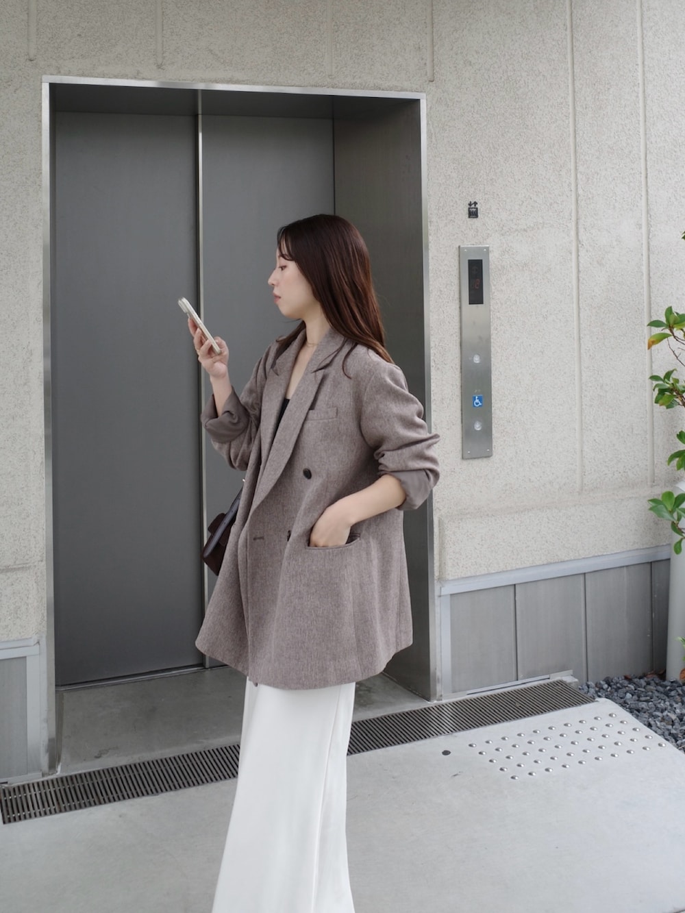 ベージュ系のテーラードジャケット、ホワイト系のスカート、ブラウン系のショルダーバッグを着用したレディースの冬コーディネートの3枚目の写真