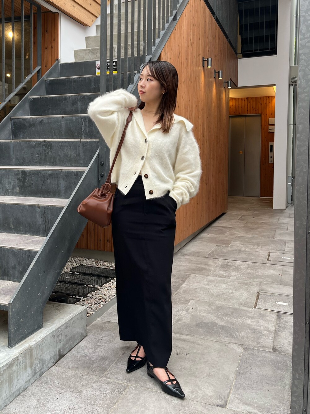 ホワイト系のカーディガン/ボレロ、ブラック系のパンプス、ブラック系のスカートを着用したレディースの秋コーディネートの3枚目の写真