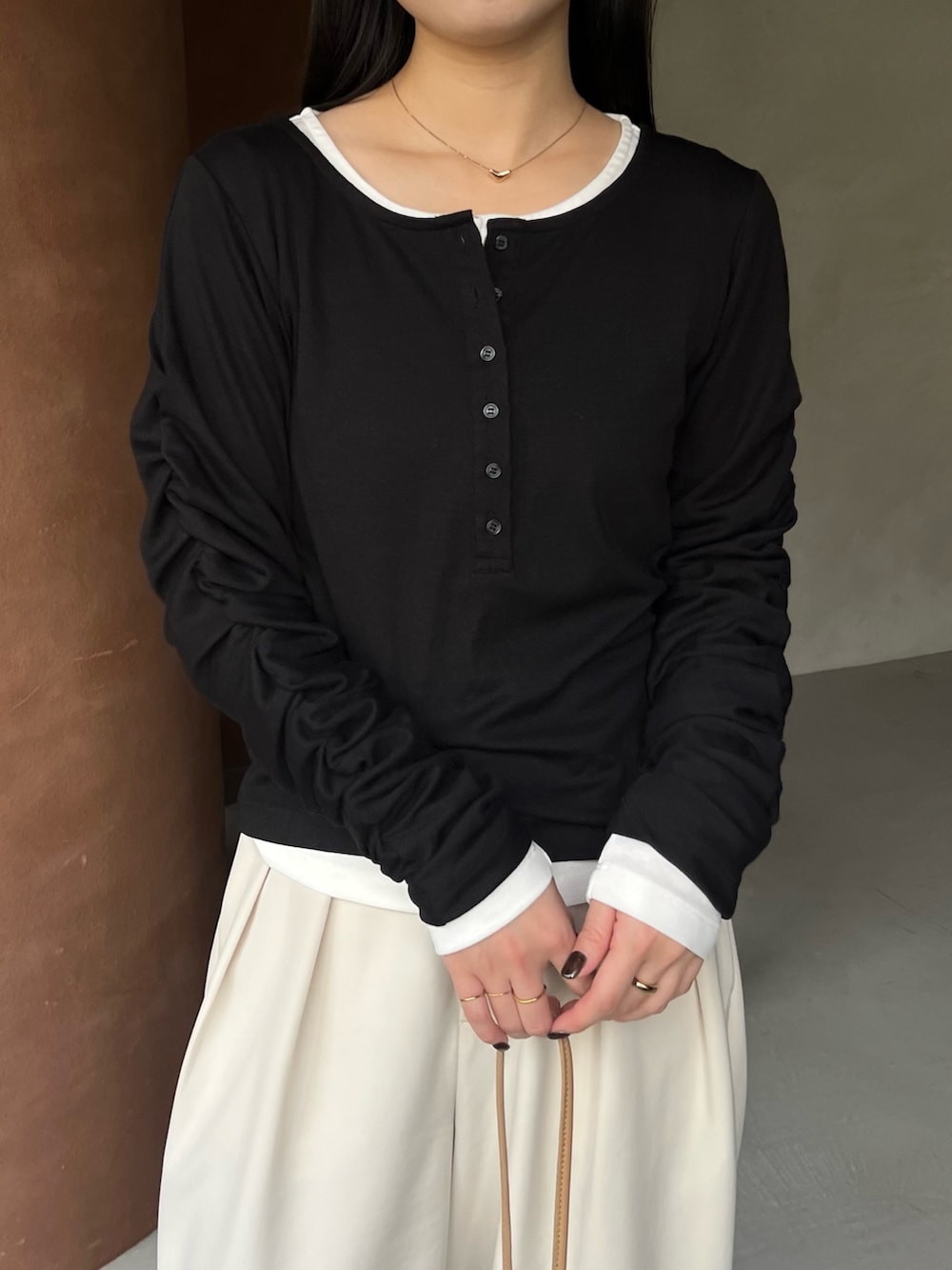 ブラック系のTシャツ/カットソー、ホワイト系のその他パンツ、ベージュ系のショルダーバッグを着用したレディースの冬コーディネートの2枚目の写真