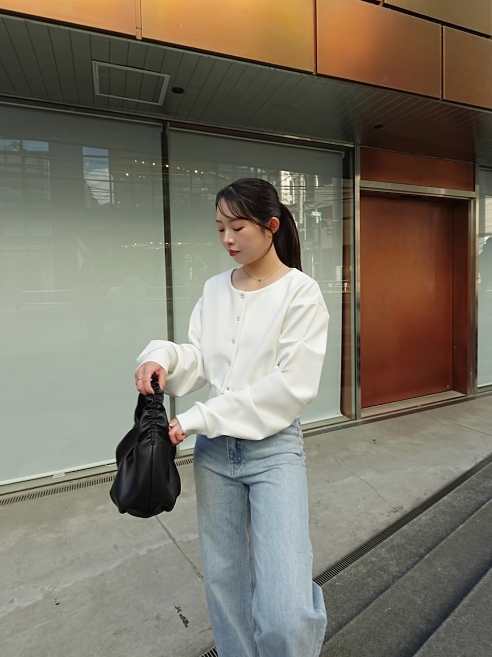 ホワイト系のTシャツ/カットソー、ブルー系のデニムパンツ、ブラック系のショルダーバッグを着用したレディースの冬コーディネートの2枚目の写真