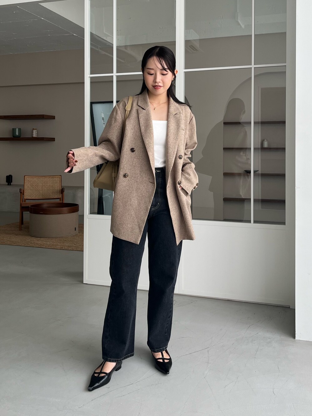 ベージュ系のテーラードジャケット、ブラック系のデニムパンツ、ブラック系のパンプスを着用したレディースの秋コーディネートの2枚目の写真