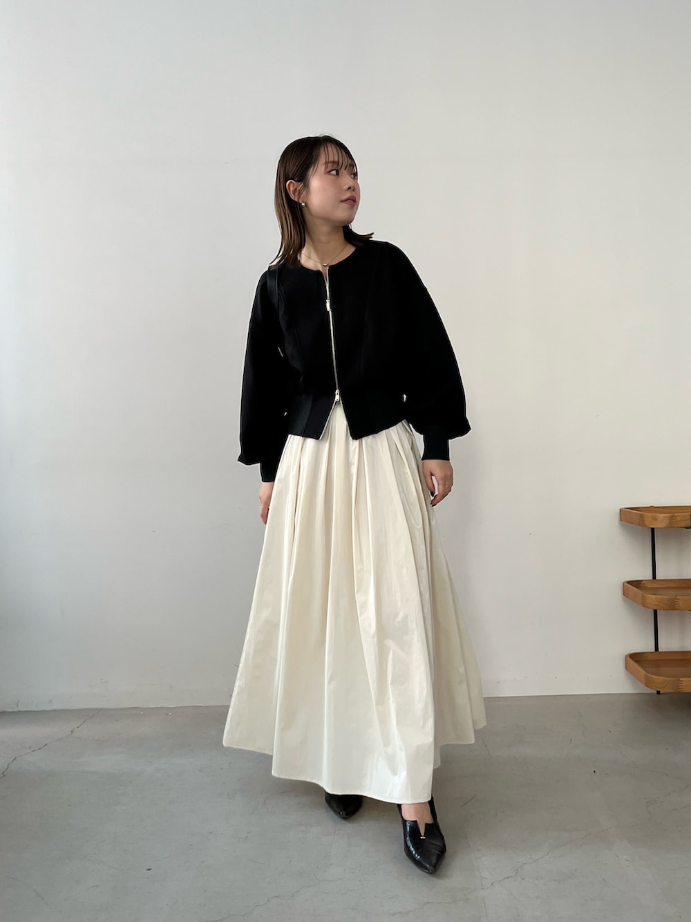 ブラック系のTシャツ/カットソー、ベージュ系のスカート、ブラック系のパンプスを着用したレディースの冬コーディネートの2枚目の写真