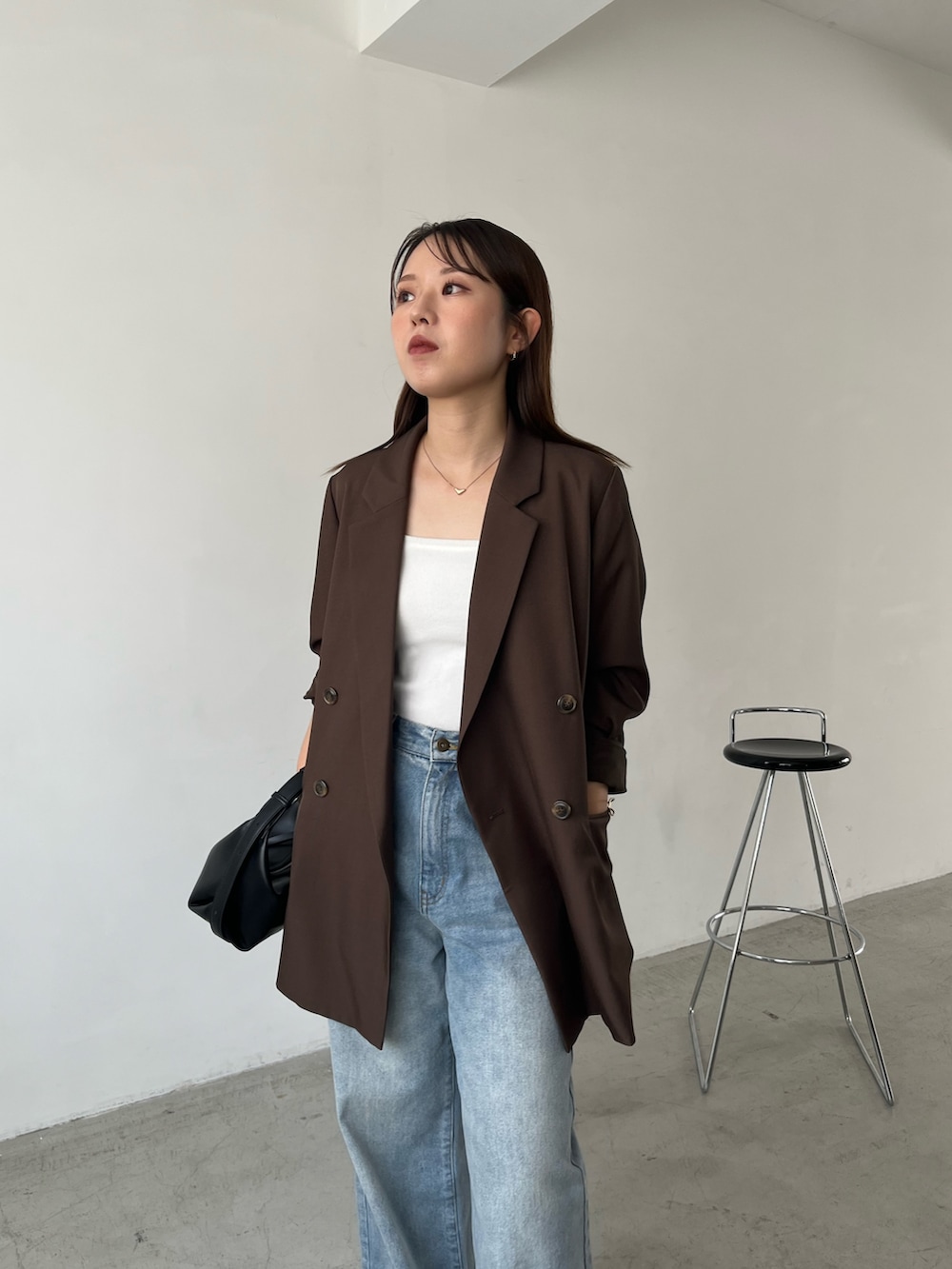 ブラウン系のテーラードジャケット、ブルー系のデニムパンツ、ブラック系のローファーを着用したレディースの秋コーディネートの5枚目の写真