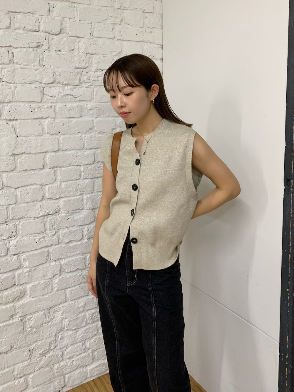 ベージュ系のニット/セーター、ブラック系のデニムパンツ、ブラック系のショルダーバッグを着用したレディースの秋コーディネートの2枚目の写真