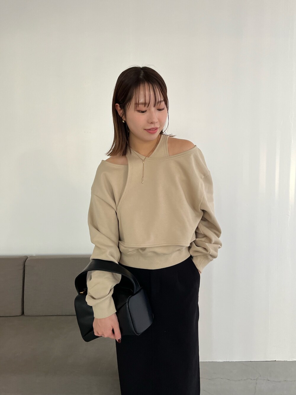 ベージュ系のスウェット、ブラック系のスカート、ブラック系のハンドバッグを着用したレディースの冬コーディネートの3枚目の写真