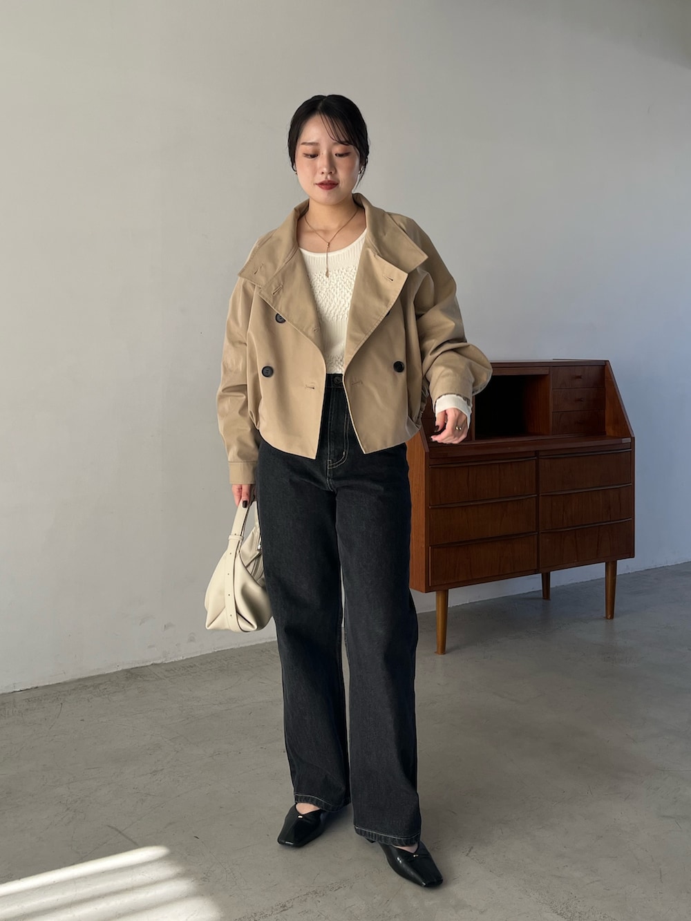 ブラック系のデニムパンツ、ブラック系のパンプス、ホワイト系のショルダーバッグを着用したレディースの冬コーディネートの3枚目の写真