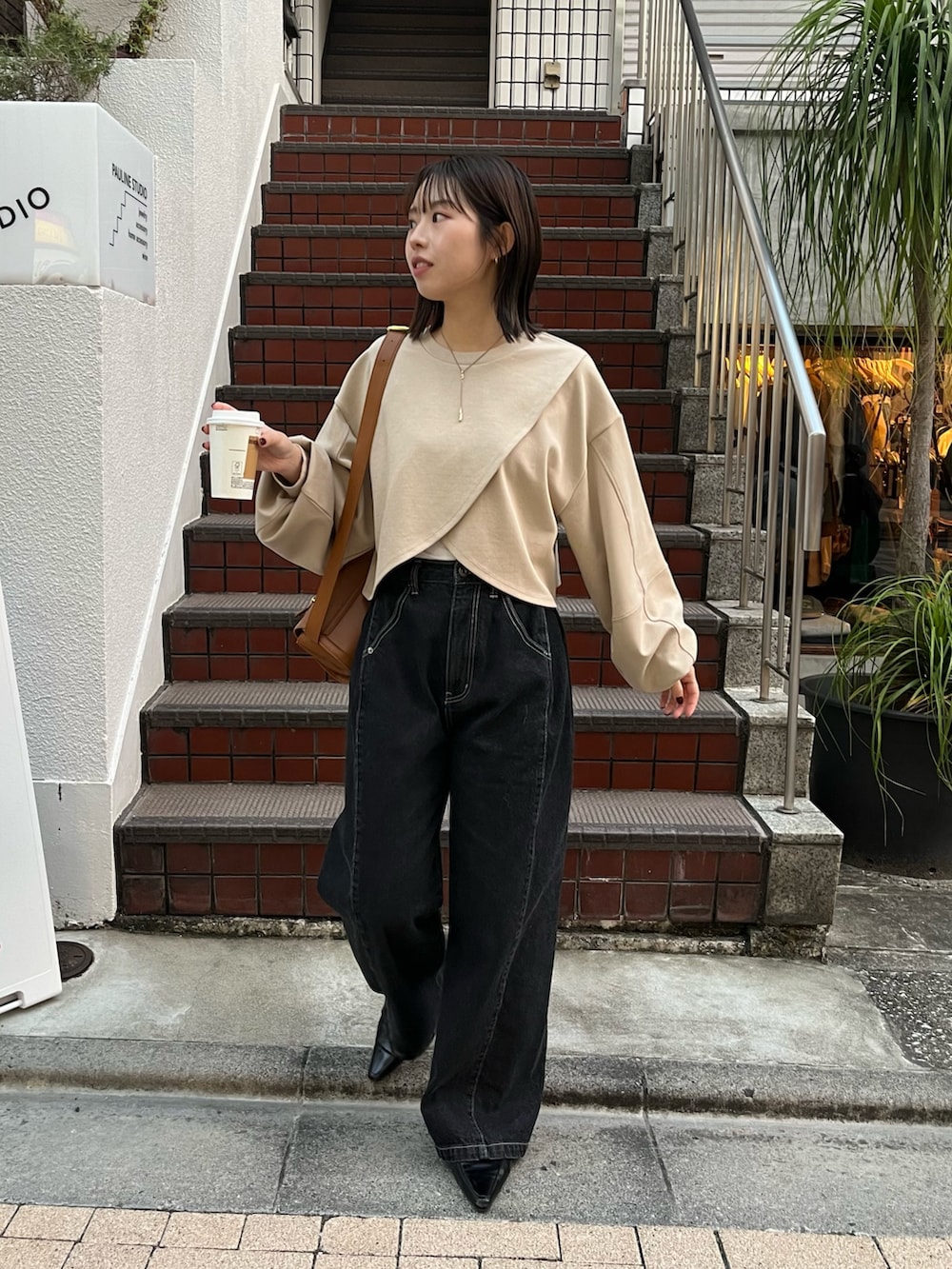 ベージュ系のTシャツ/カットソー、ベージュ系のショルダーバッグ、ブラック系のデニムパンツを着用したレディースの冬コーディネートの2枚目の写真