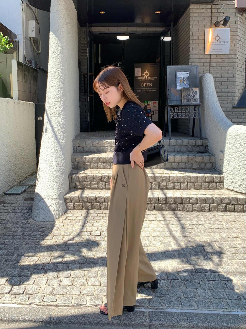 ブラック系のカーディガン/ボレロ、ベージュ系のその他パンツ、ブラック系のショルダーバッグを着用したレディースの夏コーディネートの4枚目の写真