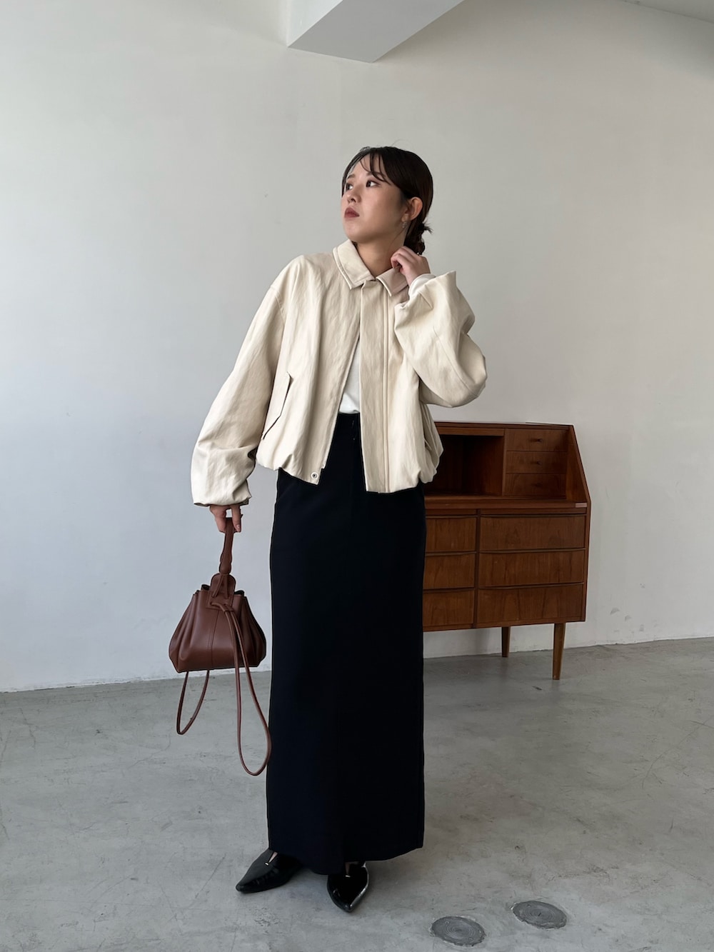 ホワイト系のブルゾン、ブラック系のスカート、ブラック系のパンプスを着用したレディースの秋コーディネートの2枚目の写真