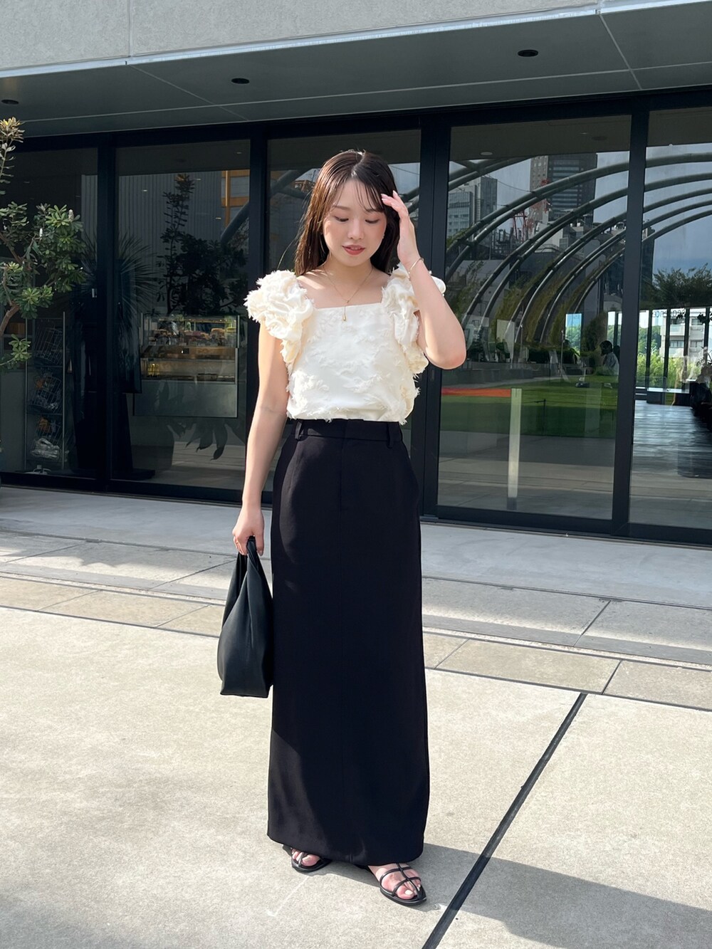 ホワイト系のシャツ/ブラウス、ブラック系のスカート、ブラック系のサンダルを着用したレディースの夏コーディネートの2枚目の写真