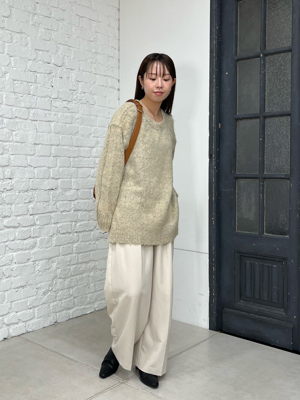 ベージュ系のニット/セーター、ホワイト系のその他パンツ、ベージュ系のショルダーバッグを着用したレディースの秋コーディネートの2枚目の写真