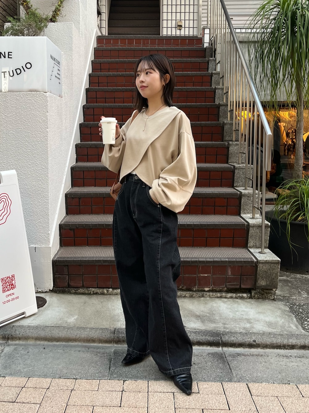 ベージュ系のTシャツ/カットソー、ベージュ系のショルダーバッグ、ブラック系のデニムパンツを着用したレディースの冬コーディネートの4枚目の写真