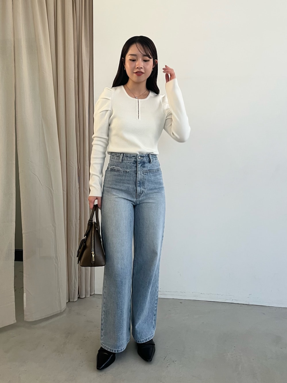 ブルー系のデニムパンツ、ブラック系のローファー、ブラウン系のショルダーバッグを着用したレディースの冬コーディネートの2枚目の写真