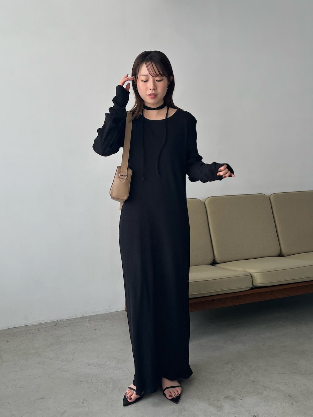 ブラック系のワンピース、ベージュ系のショルダーバッグ、ブラック系のサンダルを着用したレディースの春コーディネートの2枚目の写真