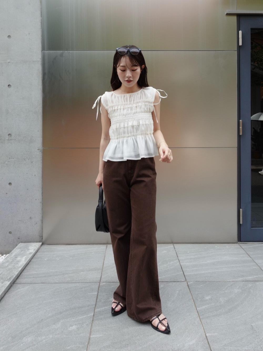 ホワイト系のシャツ/ブラウス、ブラウン系のデニムパンツ、ブラック系のショルダーバッグを着用したレディースの夏コーディネートの3枚目の写真