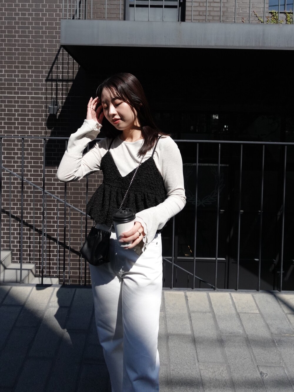 ベージュ系のTシャツ/カットソー、ブラック系のシャツ/ブラウス、ホワイト系のデニムパンツを着用したレディースの春コーディネートの3枚目の写真