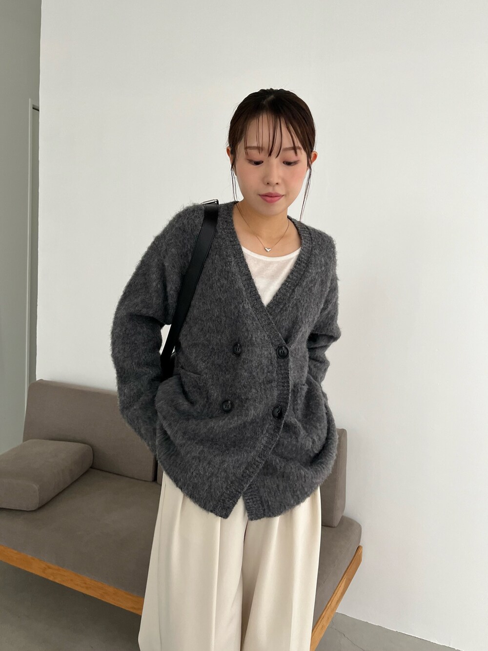 ホワイト系のTシャツ/カットソー、グレー系のカーディガン/ボレロ、ブラック系のショルダーバッグを着用したレディースの冬コーディネートの5枚目の写真