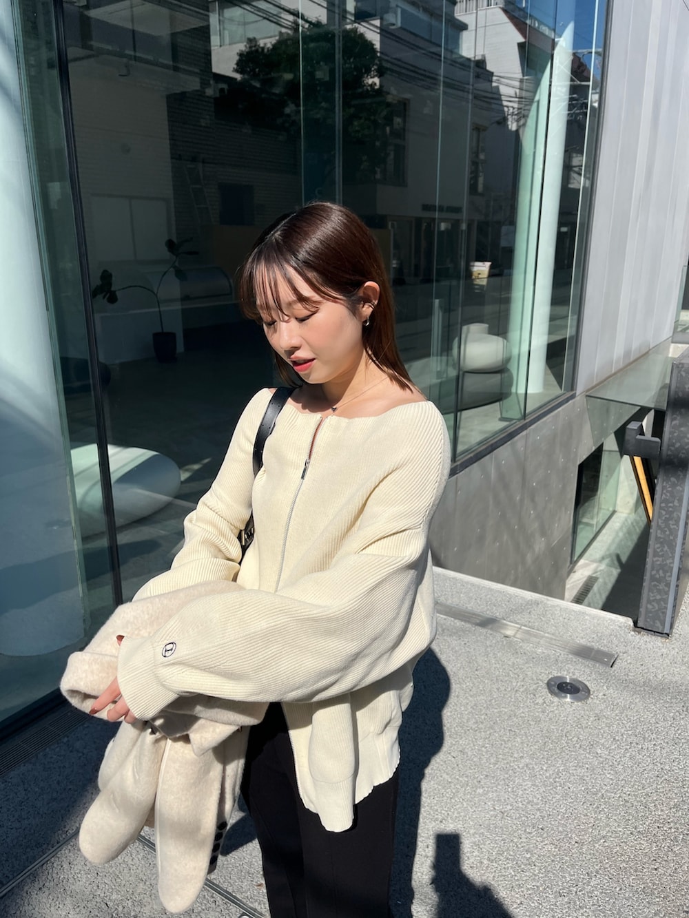 ホワイト系のニット/セーター、ベージュ系のテーラードジャケット、ブラック系のショルダーバッグを着用したレディースの春コーディネートの2枚目の写真