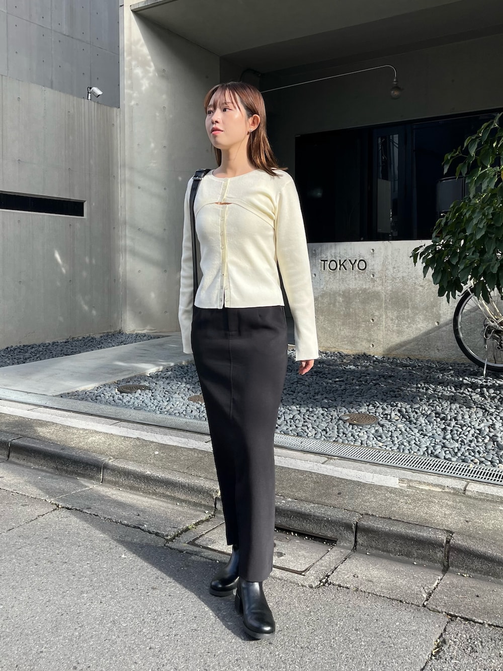 ホワイト系のニット/セーター、ブラック系のショルダーバッグ、ブラック系のスカートを着用したレディースの秋コーディネートの2枚目の写真