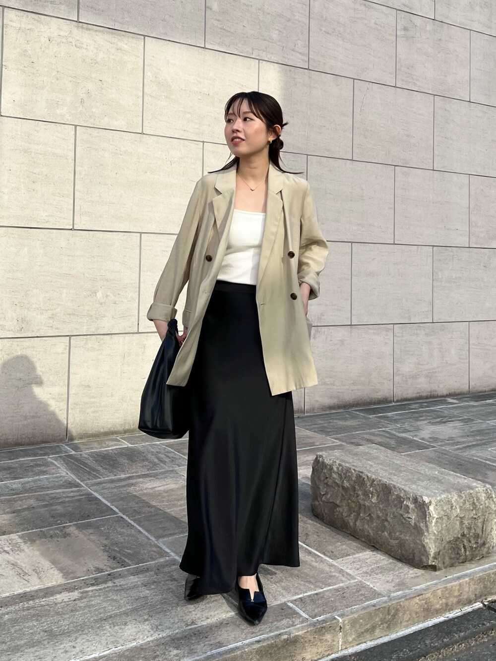 ホワイト系のキャミソール、ベージュ系のテーラードジャケット、ブラック系のスカートを着用したレディースの春コーディネートの2枚目の写真