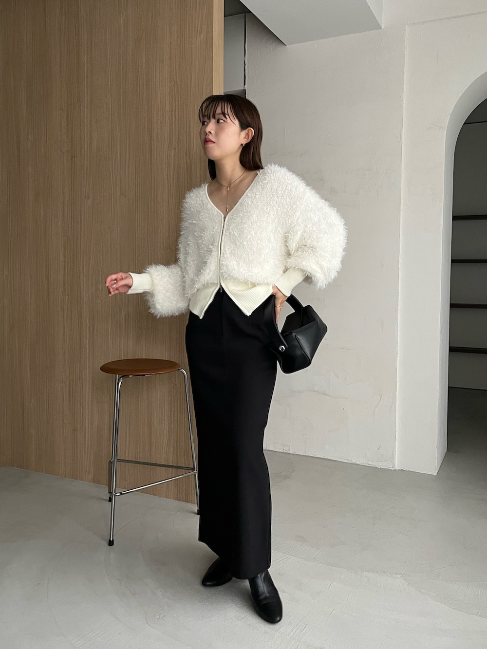 ホワイト系のカーディガン/ボレロ、ブラック系のスカート、ゴールド系のネックレスを着用したレディースの秋コーディネートの3枚目の写真