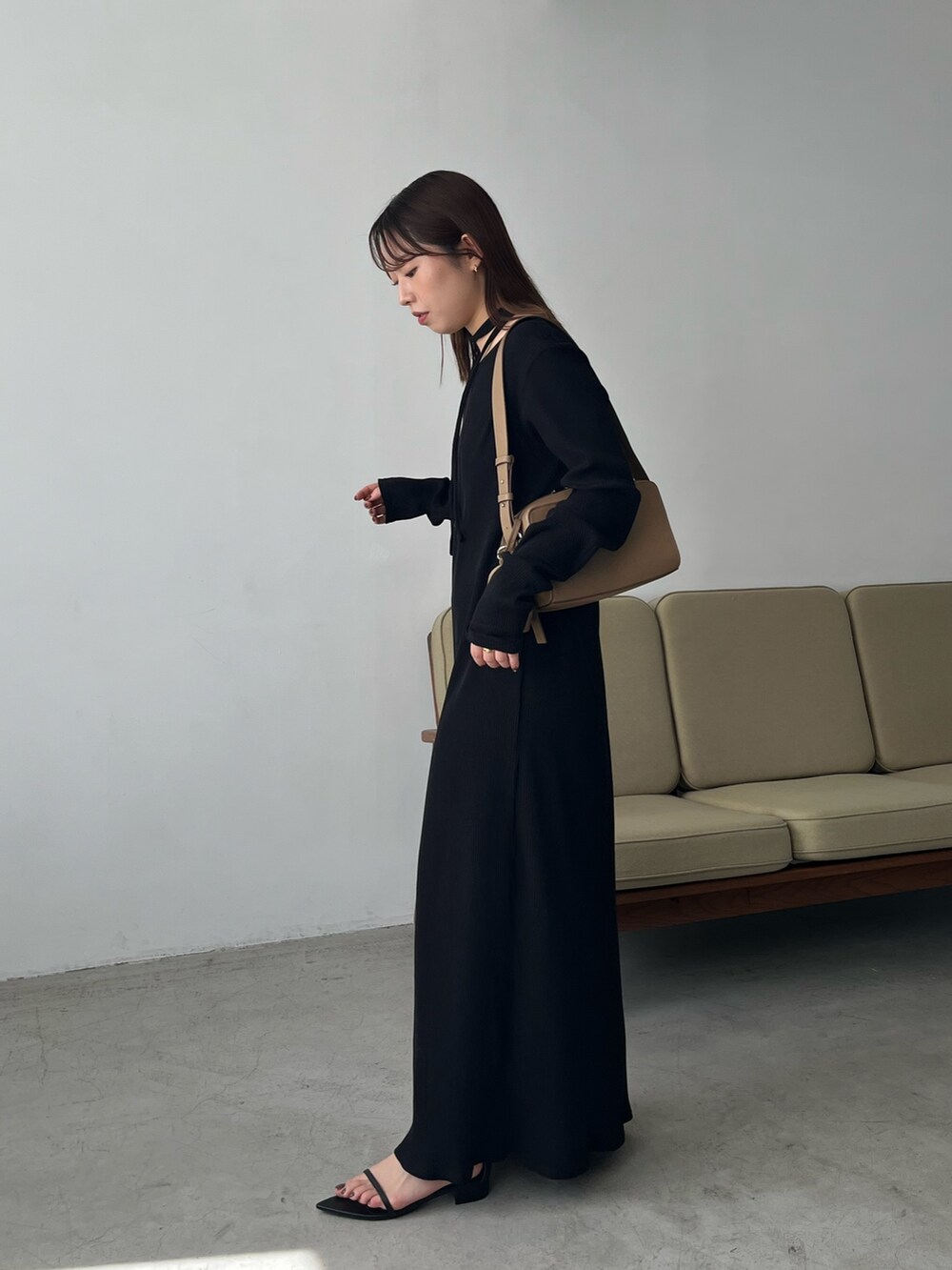 ブラック系のワンピース、ベージュ系のショルダーバッグ、ブラック系のサンダルを着用したレディースの春コーディネートの3枚目の写真
