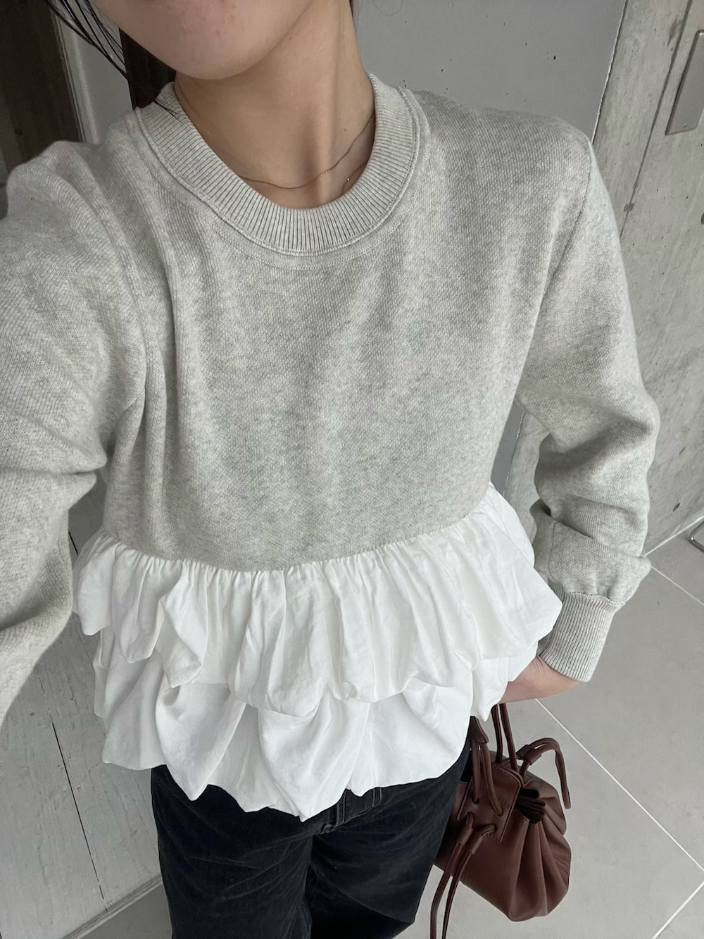 グレー系のニット/セーター、ブラック系のデニムパンツ、ブラック系のローファーを着用したレディースの冬コーディネートの3枚目の写真