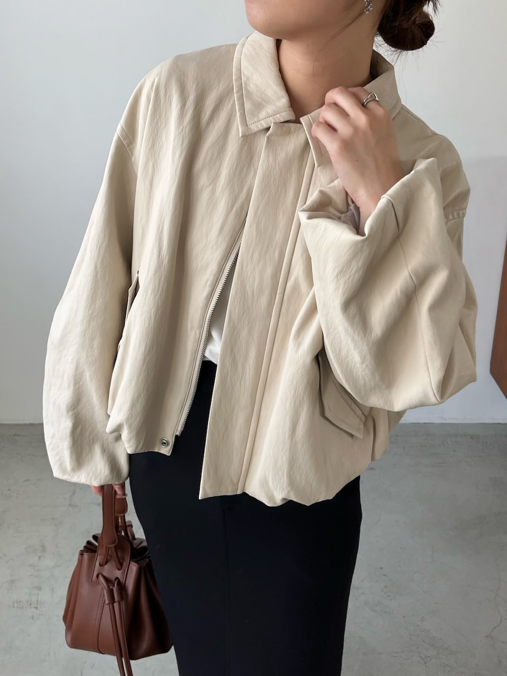 ホワイト系のブルゾン、ブラック系のスカート、ブラック系のパンプスを着用したレディースの秋コーディネートの3枚目の写真