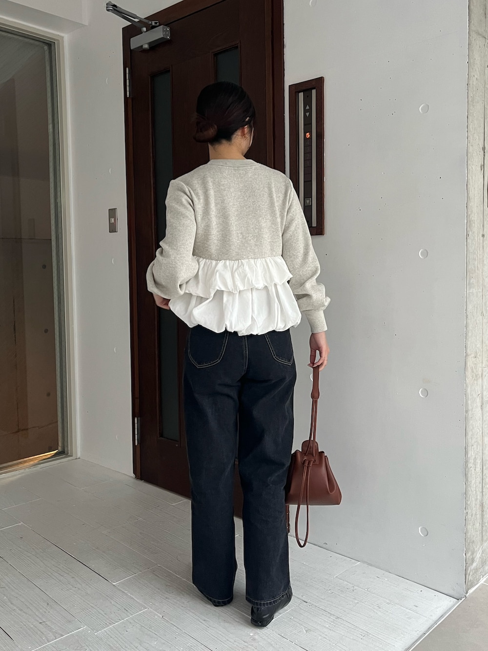 グレー系のニット/セーター、ブラック系のデニムパンツ、ブラック系のローファーを着用したレディースの冬コーディネートの5枚目の写真