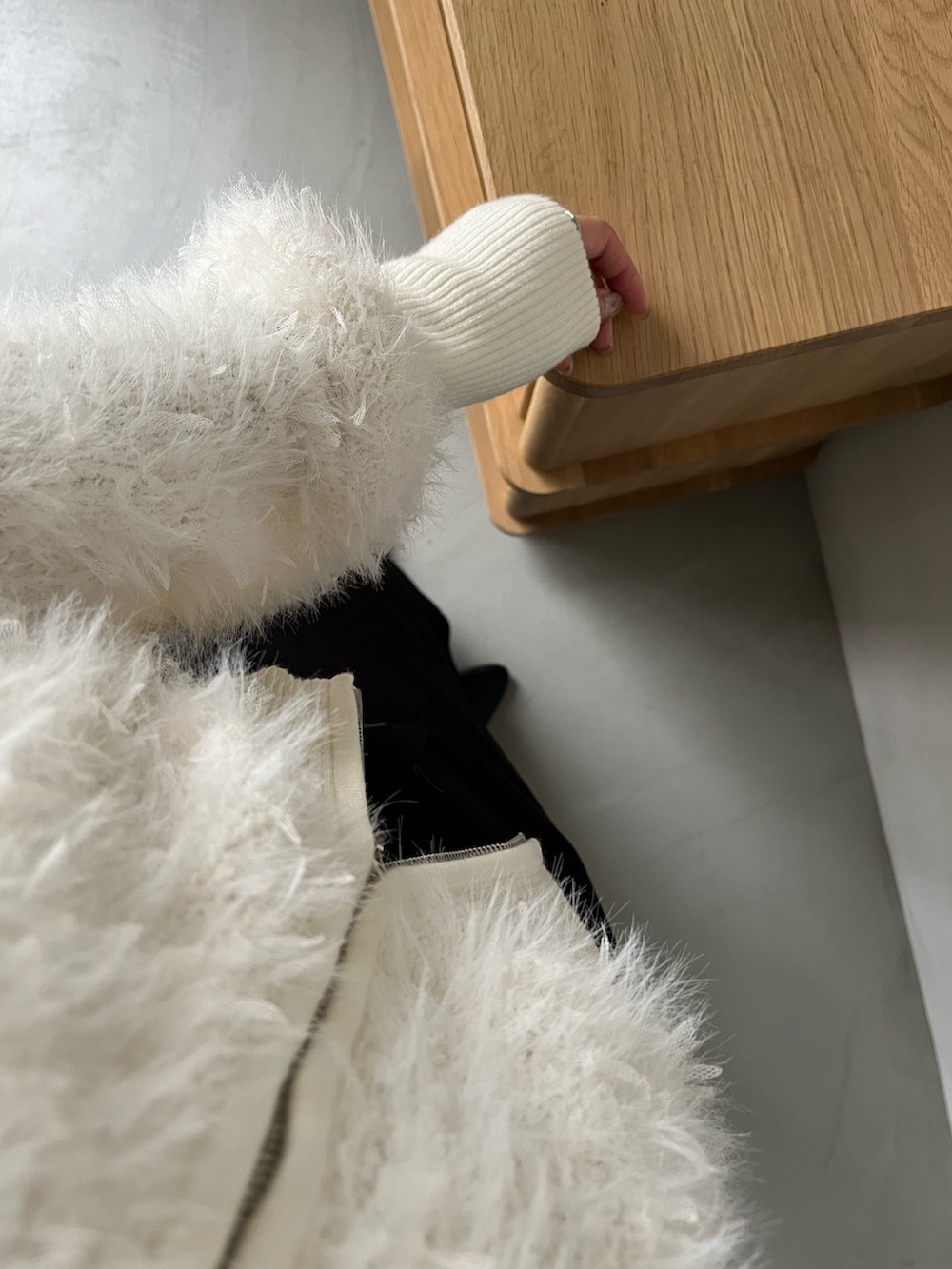 ホワイト系のカーディガン/ボレロ、ブラック系のスカート、ゴールド系のネックレスを着用したレディースの秋コーディネートの6枚目の写真