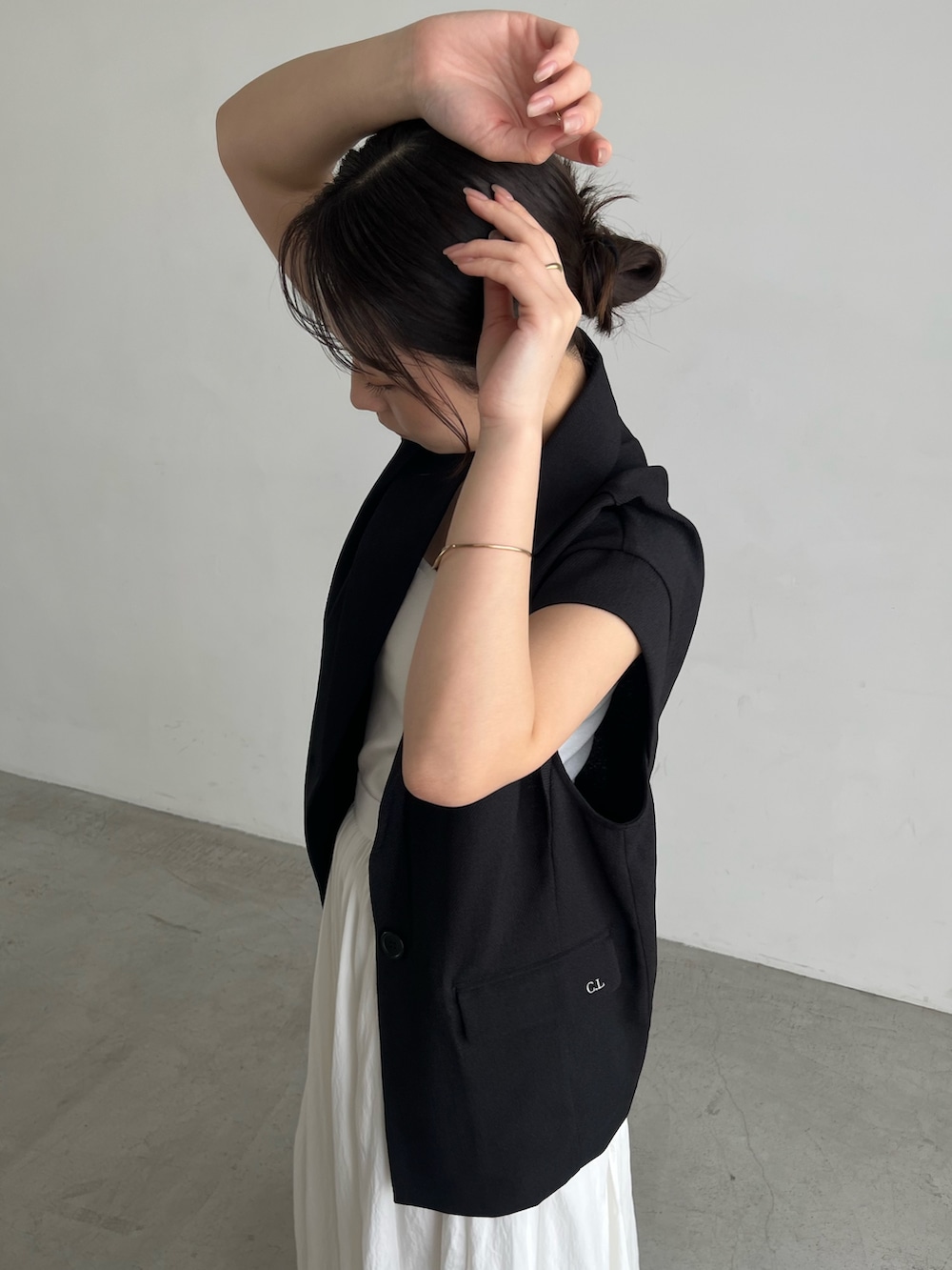 ホワイト系のキャミソール、ホワイト系のスカート、ブラック系のパンプスを着用したレディースの夏コーディネートの4枚目の写真