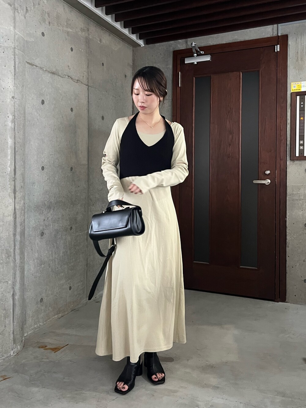 ベージュ系のワンピース、ブラック系のショルダーバッグ、ブラック系のブーツを着用したレディースの春コーディネートの2枚目の写真