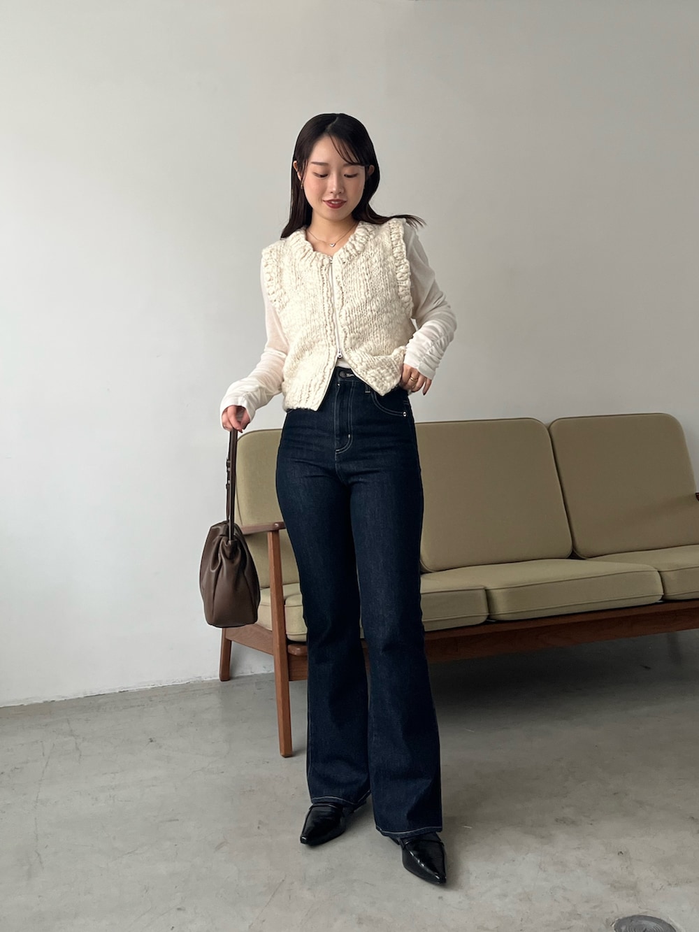 ホワイト系のTシャツ/カットソー、ホワイト系のニット/セーター、ブルー系のデニムパンツを着用したレディースの秋コーディネートの3枚目の写真