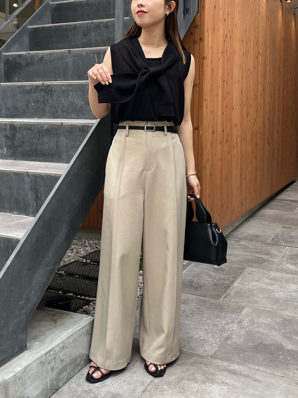 ブラック系のニット/セーター、ベージュ系のその他パンツ、ブラック系のサンダルを着用したレディースの夏コーディネートの2枚目の写真
