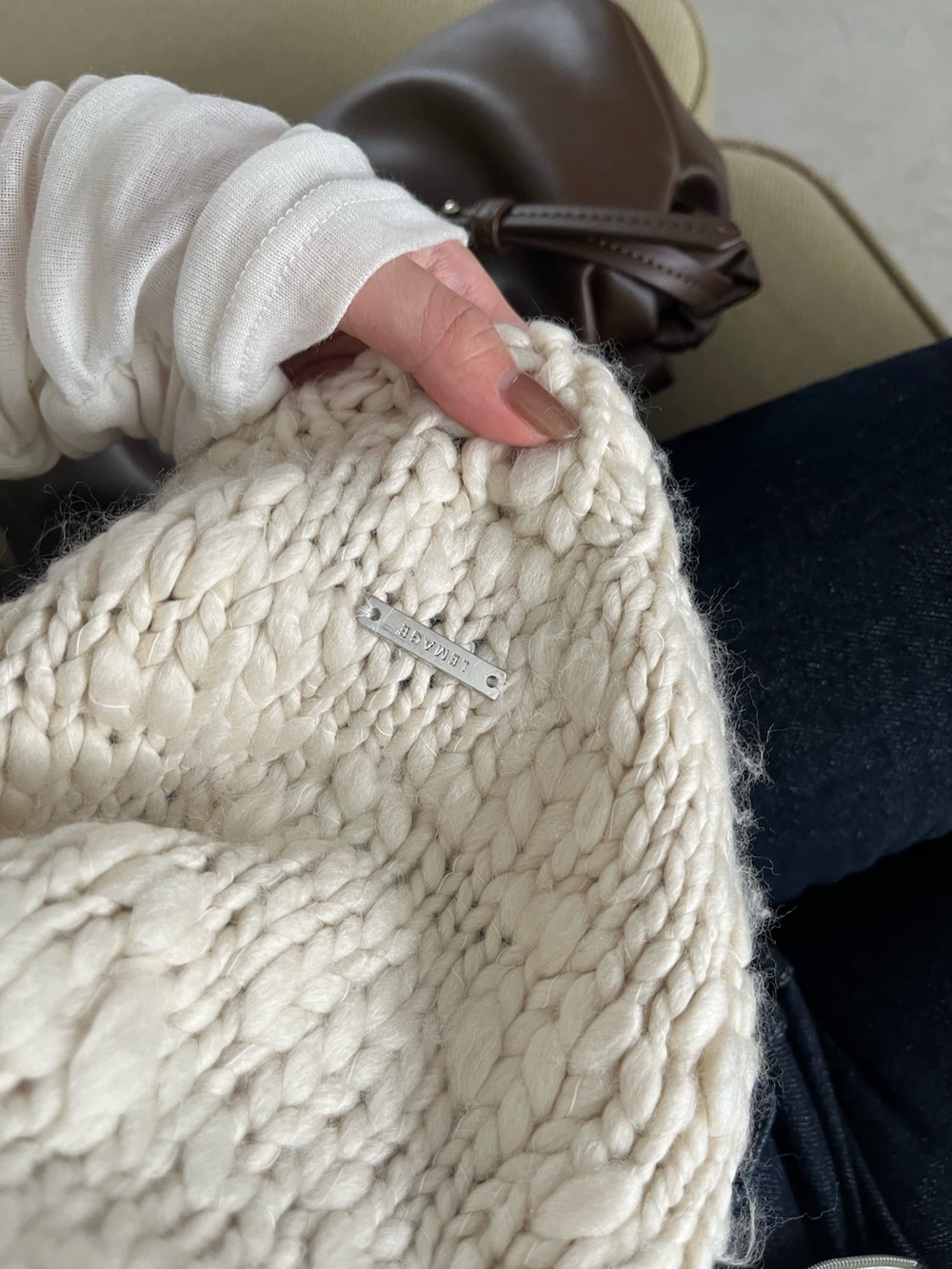 ホワイト系のTシャツ/カットソー、ホワイト系のニット/セーター、ブルー系のデニムパンツを着用したレディースの秋コーディネートの5枚目の写真