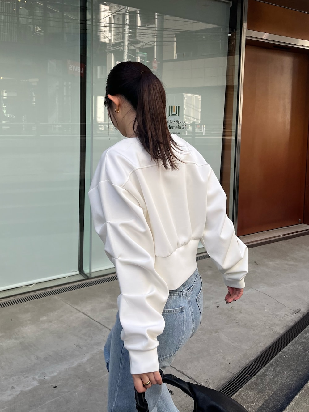 ホワイト系のTシャツ/カットソー、ブルー系のデニムパンツ、ブラック系のショルダーバッグを着用したレディースの冬コーディネートの5枚目の写真