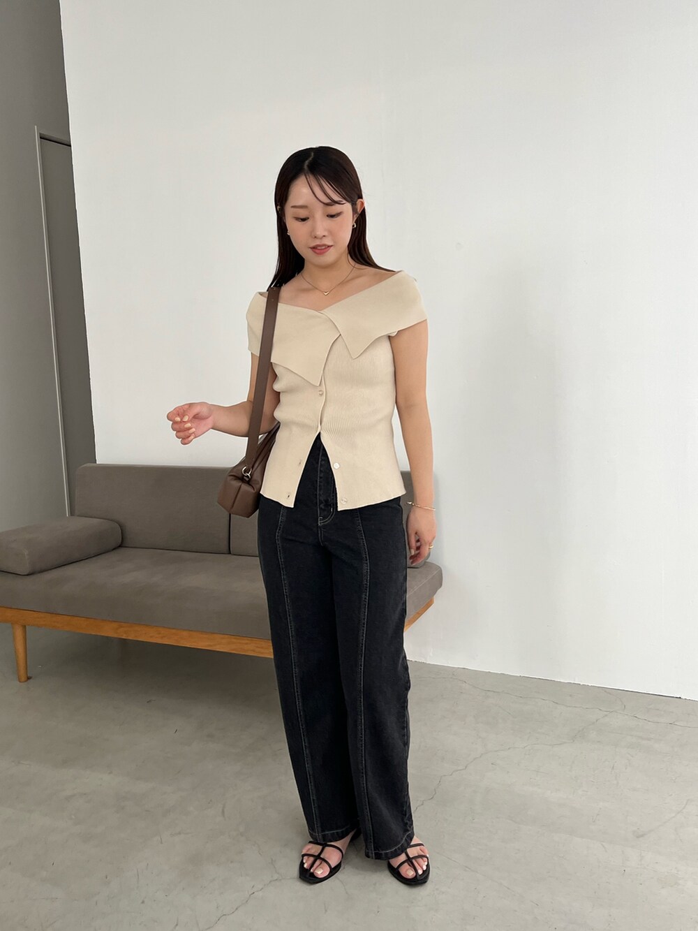 ブラック系のデニムパンツ、ベージュ系のニット/セーター、ブラック系のサンダルを着用したレディースの夏コーディネートの2枚目の写真