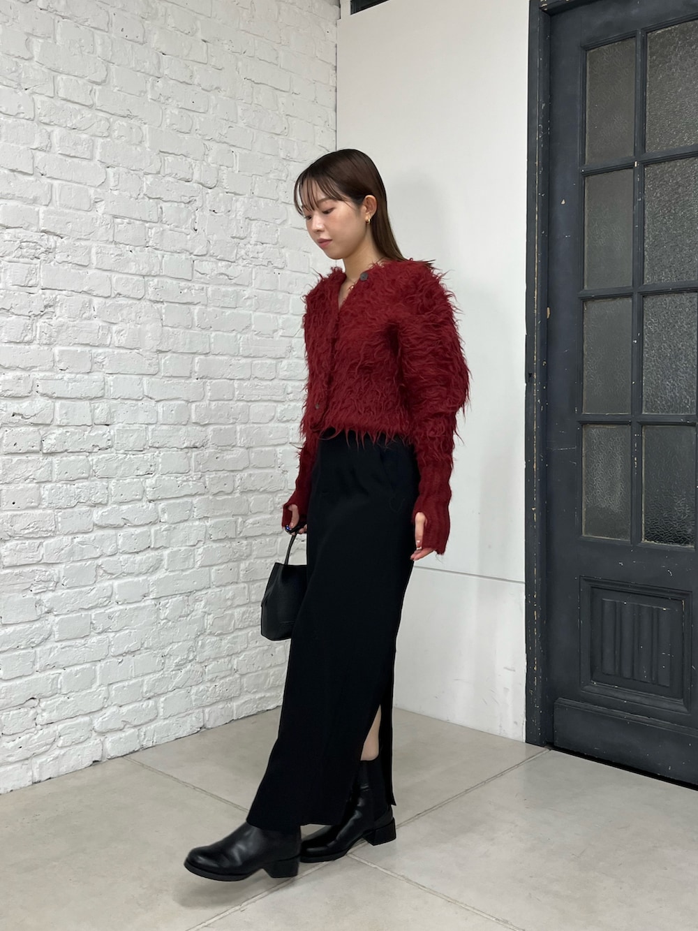 レッド系のカーディガン/ボレロ、ブラック系のスカート、ブラック系のショルダーバッグを着用したレディースの秋コーディネートの2枚目の写真