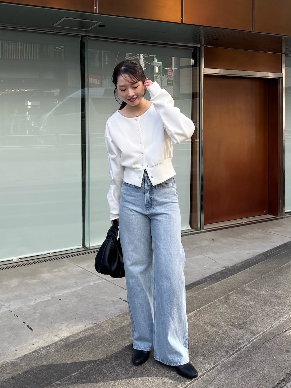 ホワイト系のTシャツ/カットソー、ブルー系のデニムパンツ、ブラック系のショルダーバッグを着用したレディースの冬コーディネートの3枚目の写真