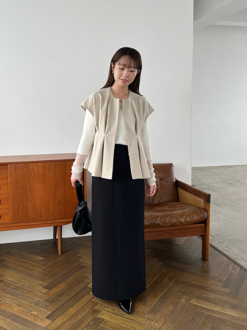 ホワイト系のニット/セーター、ブラック系のハンドバッグ、ブラック系のパンプスを着用したレディースの秋コーディネートの2枚目の写真