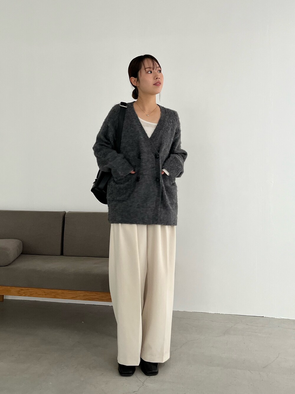 ホワイト系のTシャツ/カットソー、グレー系のカーディガン/ボレロ、ブラック系のショルダーバッグを着用したレディースの冬コーディネートの3枚目の写真