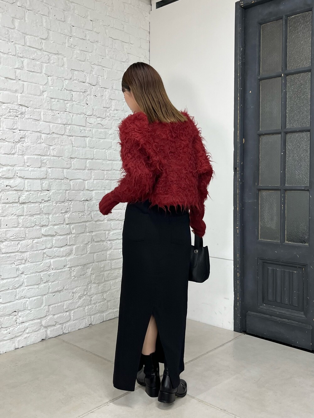 レッド系のカーディガン/ボレロ、ブラック系のスカート、ブラック系のショルダーバッグを着用したレディースの秋コーディネートの4枚目の写真