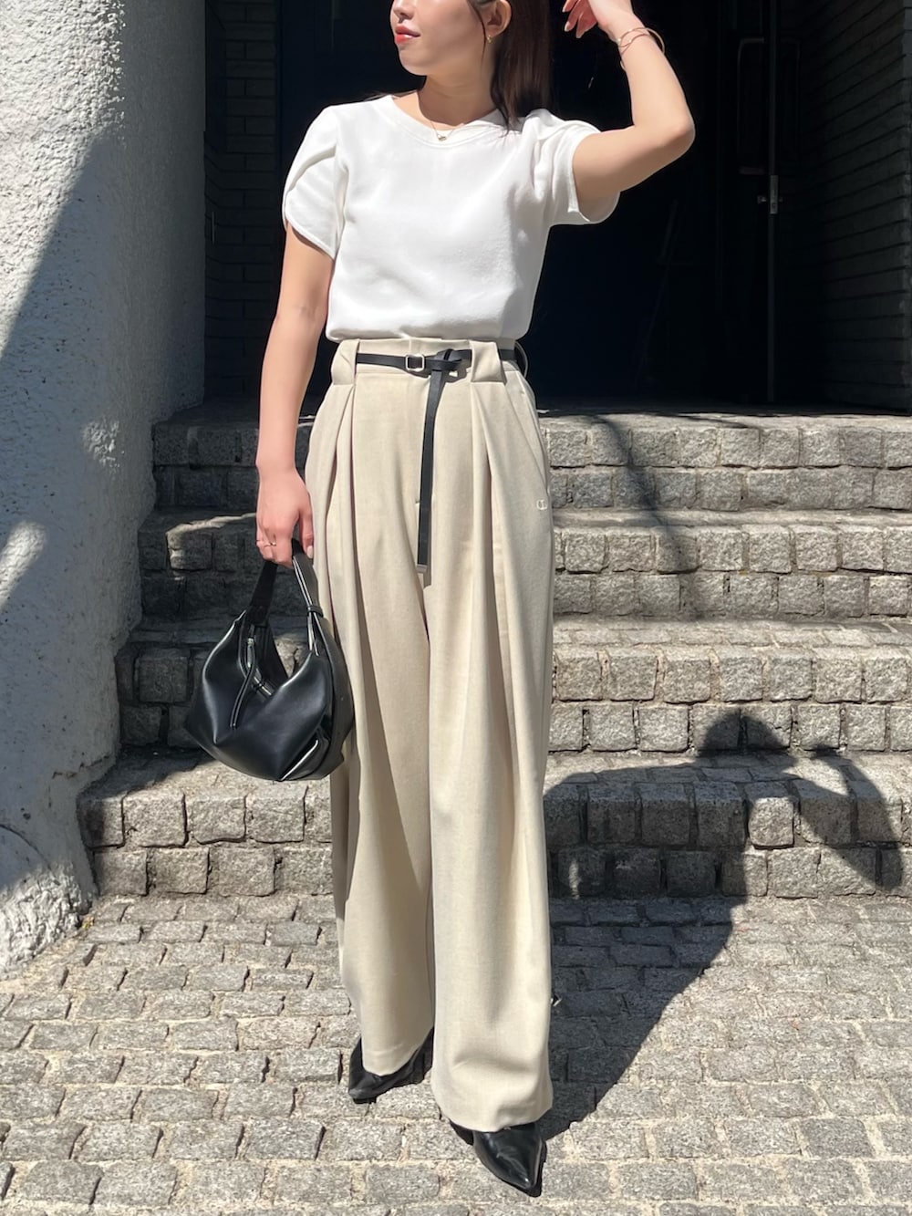 ホワイト系のニット/セーター、ベージュ系のその他パンツ、ブラック系のショルダーバッグを着用したレディースの春コーディネートの2枚目の写真