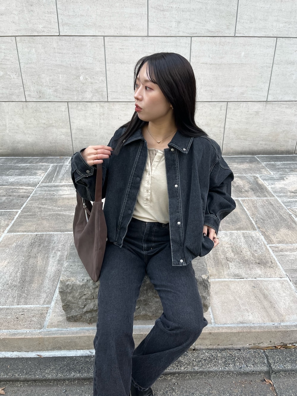 ブラック系のブルゾン、ベージュ系のTシャツ/カットソー、ブラック系のデニムパンツを着用したレディースの冬コーディネートの5枚目の写真