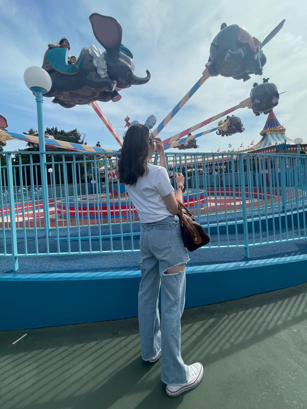 ホワイト系のTシャツ/カットソー、ブルー系のデニムパンツ、ブラウン系のボストンバッグを着用したレディースの夏コーディネートの2枚目の写真