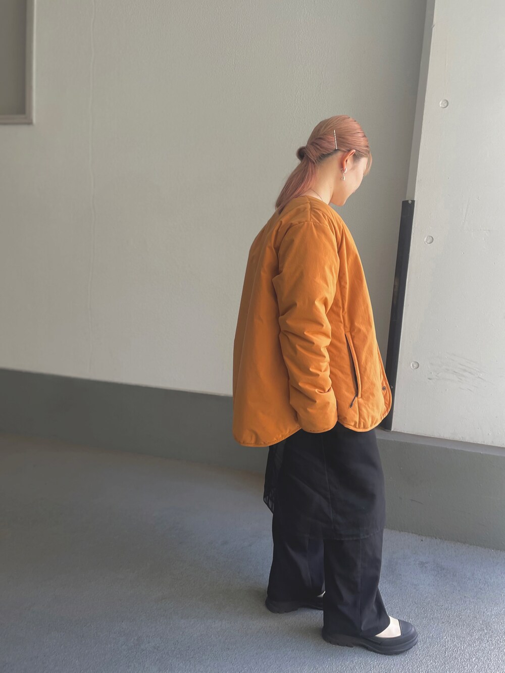 オレンジ系のノーカラーコート、ブラック系のワンピース、ベージュ系のブーツを着用したレディースの秋コーディネートの2枚目の写真