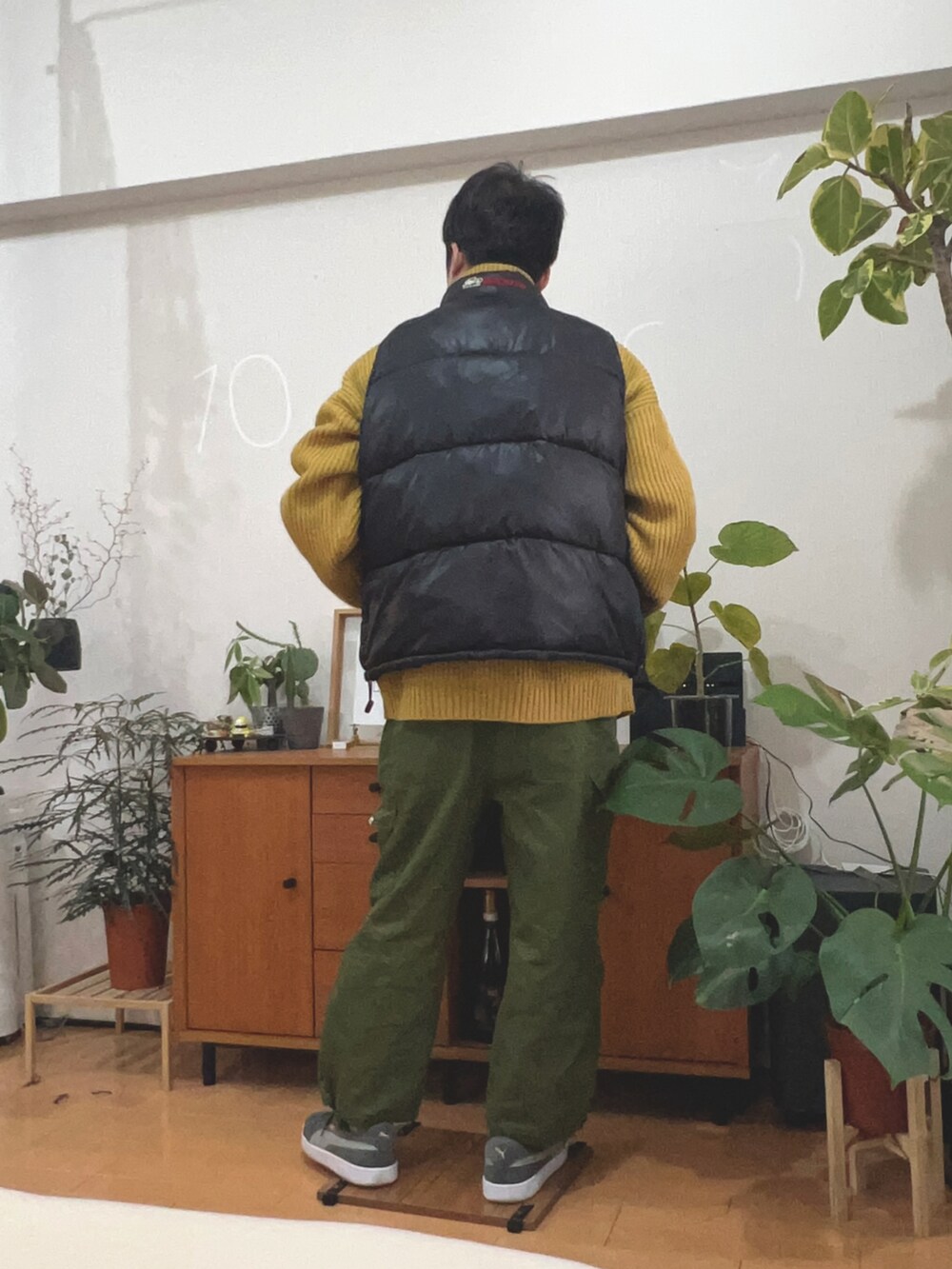 グリーン系のカーゴパンツ、ブラック系のダウンベスト、グレー系のスニーカーを着用したメンズの冬コーディネートの2枚目の写真